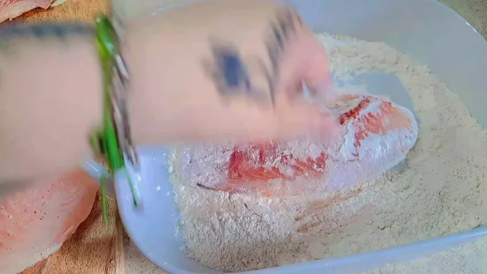 Dredge the tilapia fillets in the seasoned flour, then dip into the batter, ensuring they are fully coated.