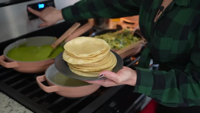 Preheat oven to 350°F (175°C). Assemble enchiladas: Fill each tortilla with the chicken mixture, roll, and place in a baking sheet.