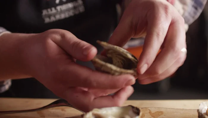 Once oysters are cool enough to handle, pry open the top shell and carefully separate the oyster from the top shell. Return the oyster to the bottom shell.