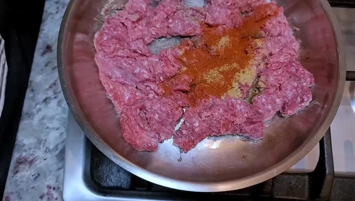 Season the ground beef with 1 teaspoon beef bouillon powder, 1/2 teaspoon smoked paprika, 2 teaspoons chili powder, 1/2 teaspoon ground cumin, and 1/2 teaspoon garlic powder. Add dehydrated minced onion.