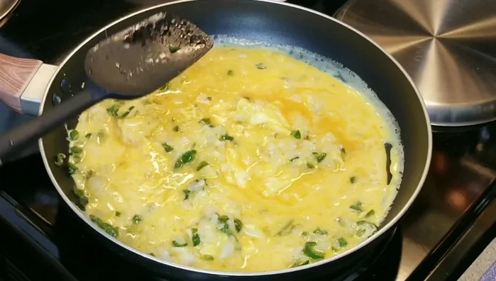 Once partially cooked, gently move the curdled egg to the middle, letting it continue to cook.