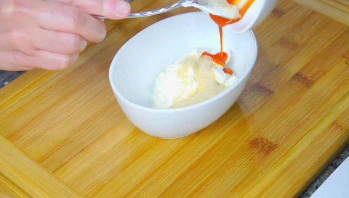 Make the sauce by mixing mayonnaise, sour cream, minced garlic, hot sauce, honey, salt, lime juice, and white vinegar. (Exact measurements are in the video description).
