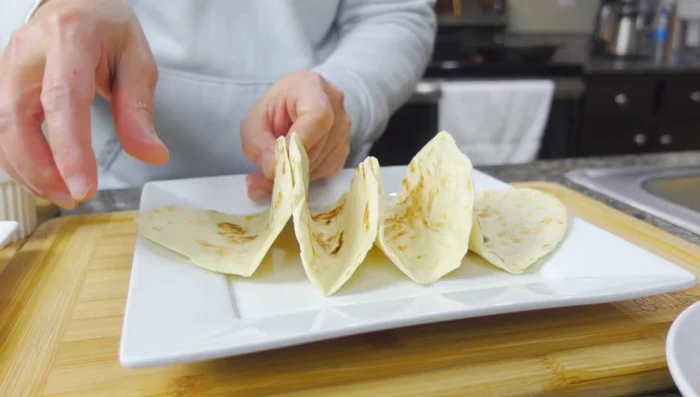 Assemble the tacos: Layer purple cabbage, avocado, red onion, fish, cheese, and sauce in each shell.