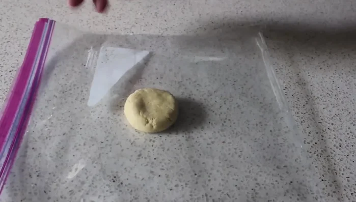 Place a dough ball between two layers of a Ziploc bag and flatten it to about ⅛ inch thickness using a flat, heavy object.