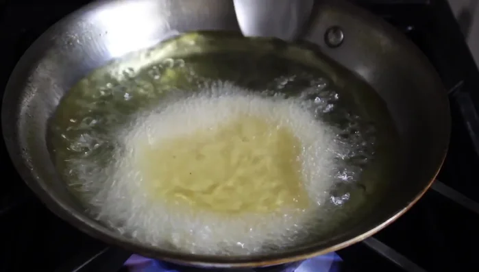 Baste the top of the tortilla with hot oil to ensure even cooking and puffing.