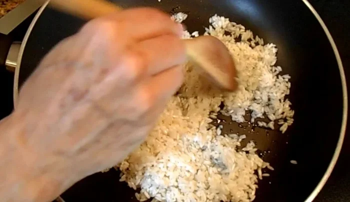 Heat vegetable oil in a large skillet over high heat. Add the washed rice and fry until it becomes slightly darker, stirring constantly. This prevents mushy rice.