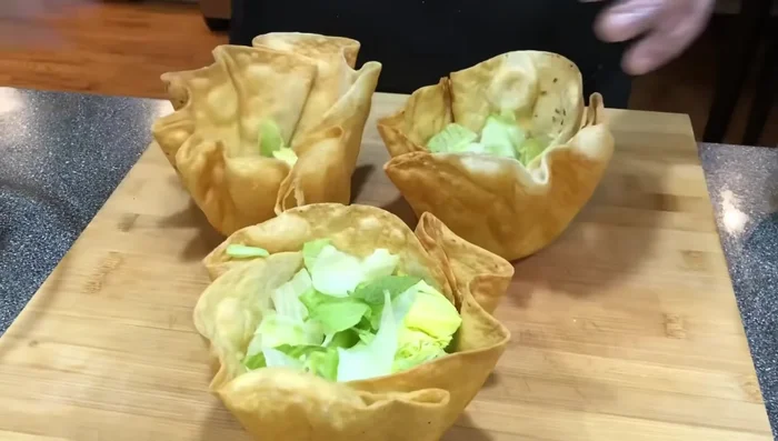 Assemble the salad. Layer lettuce, taco meat, shredded cheese, diced onions, and diced tomatoes into the cooled tortilla bowls.