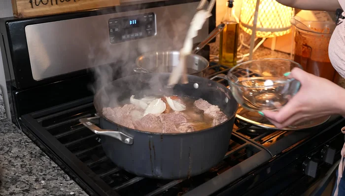 Remove onion and garlic from the simmering meat. Add the blended adobo sauce and additional beef broth as needed. Strain if desired.