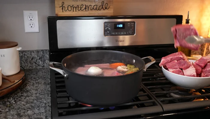 Add 2 lbs of short ribs and 5 lbs of chuck pot roast to the pot. Bring back to a boil, then skim off impurities.