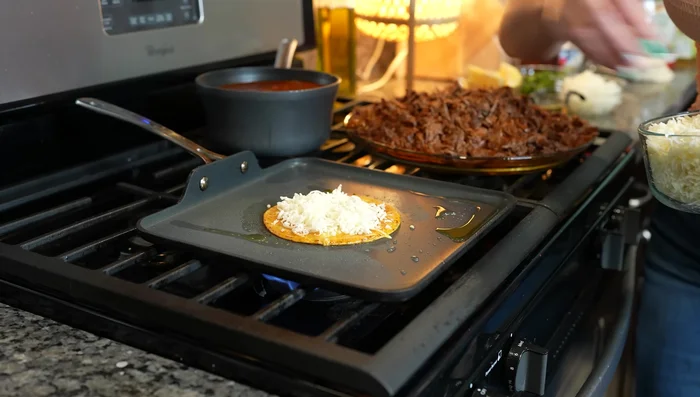 Add cheese to the tortillas and let it melt. Add birria, onions, cilantro, and lime juice. Fold and serve.