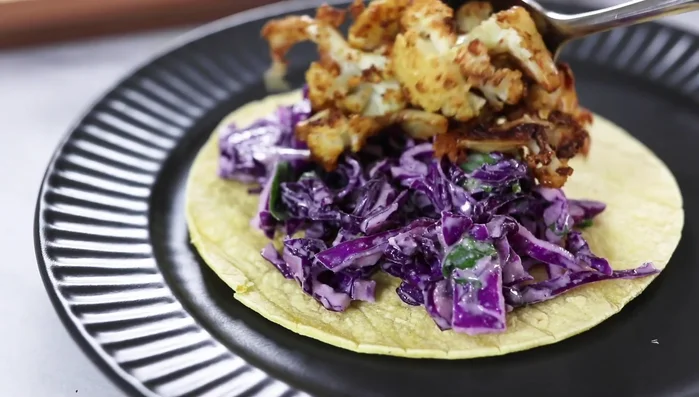 Assemble tacos: Add coleslaw, roasted cauliflower, and optional toppings (avocado, green onions).