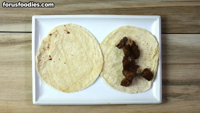 Assemble the tacos: Add the cooked meat, red onion, cilantro, and feta cheese to the tortillas.