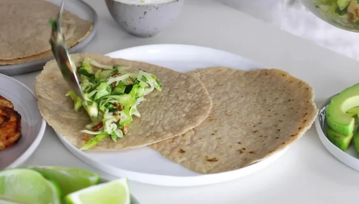 Assemble tacos: Place tortillas on a plate. Add slaw, avocado slices, shrimp, and drizzle with lime crema. (288.88)