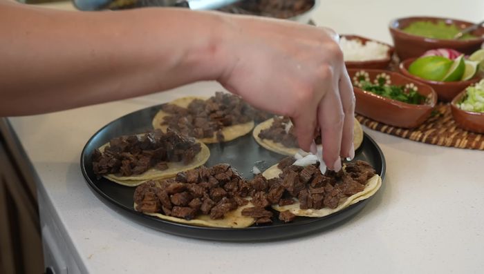 Assemble tacos: Warm tortillas and fill with cooked beef, onion, cilantro, cabbage, salsas, radish, and jalapeno, as desired. (423.3)