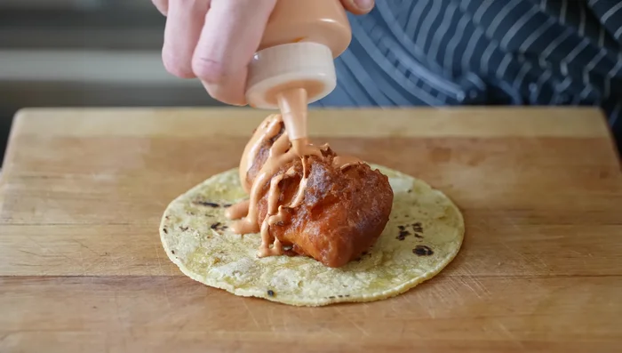 Assemble the fried fish tacos: Warm tortillas. Fill with fried fish, chili crema, and cabbage slaw.