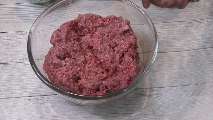 In a bowl, combine ground beef, minced garlic, rice, egg, spices (coriander, cumin, oregano, thyme, black pepper), and most of the chopped cilantro. Mix well until all ingredients are completely integrated.