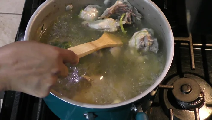 Remove the onion, cilantro, and garlic from the cooked chicken.