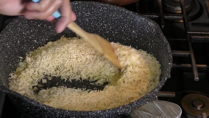 Add the fried rice to the pan with the vegetables. Add another 2 cups of water, serrano chilies, peas, cilantro, and salt. Stir to combine.