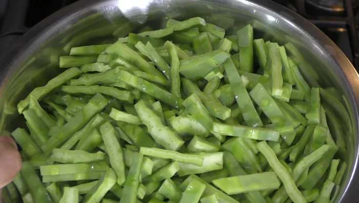Boil water in a pot. Add nopales, a teaspoon of salt, some cilantro sprigs, a quarter of an onion, and two tomato peels to remove slime. Cover and cook for about 18 minutes, stirring occasionally.