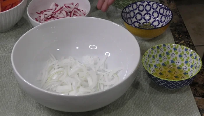 In a container, combine chopped onion, radishes, and serrano chili (if using).