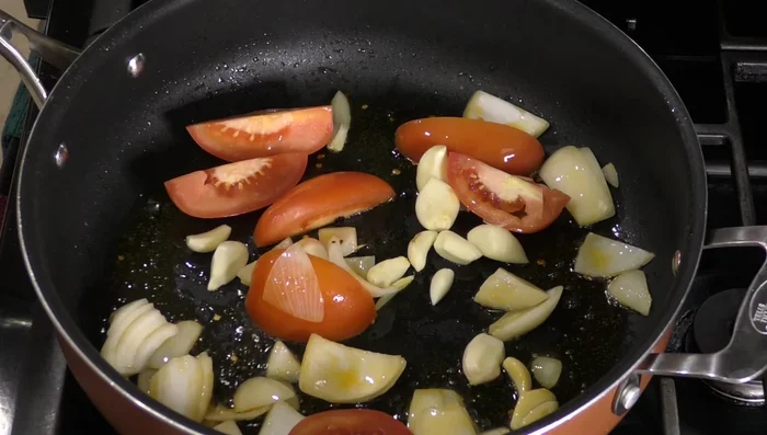 Sauté chopped onion, tomatoes, and garlic. Add cumin, thyme, oregano, bay leaf, and cloves.