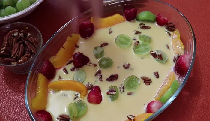 Once semi-set, arrange more strawberries, peaches, grapes, and chopped walnuts on top. Add more of the three-milk mixture, then refrigerate again until semi-set.