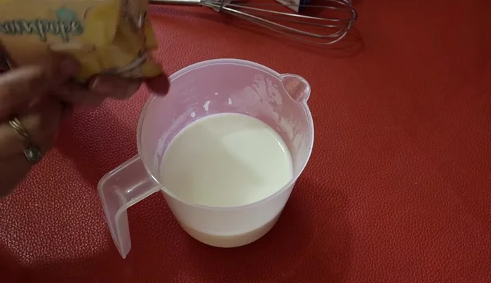 In a bowl, combine the two packages of eggnog-flavored gelatin with two cups of boiling milk. Stir until lumps dissolve. Let it rest for 10 minutes, then stir again.