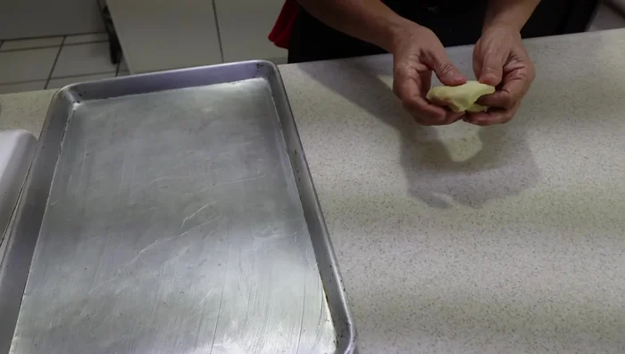Place the dough balls onto a buttered baking tray, leaving space between each.