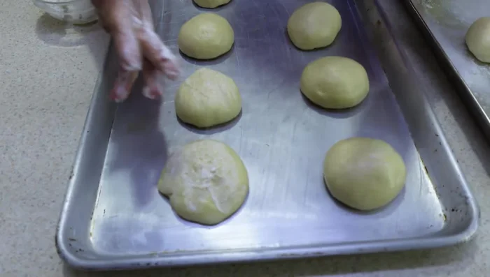 Top each dough ball with a small portion of the topping dough, flattening it slightly. Make the traditional cuts on top of the dough.