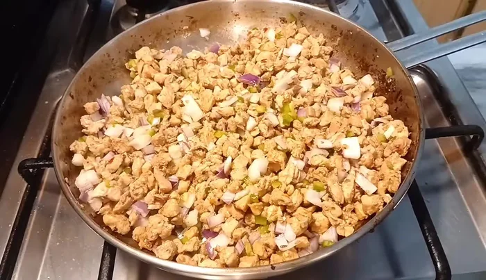Add chopped onion and capsicum to the cooked chicken. Add more chilli sauce if desired.