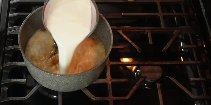 Once the piloncillo is dissolved, add whole milk, condensed milk, evaporated milk, and a cinnamon stick. Stir well.