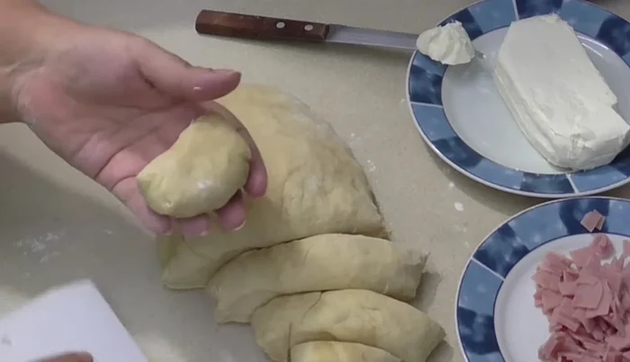 Shape the balls: Roll the dough into small balls. Flatten each ball, add a piece of ham and cream cheese, then seal.