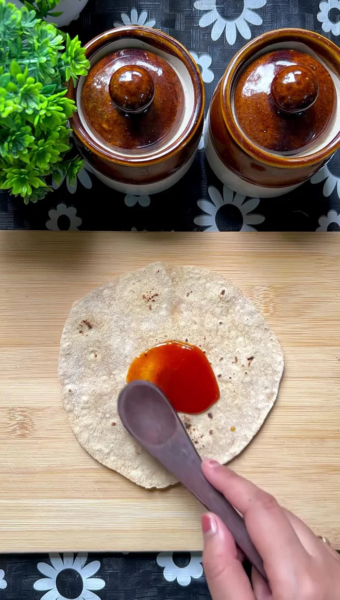 To make the taco shells, spread tomato sauce on one side of each leftover roti.