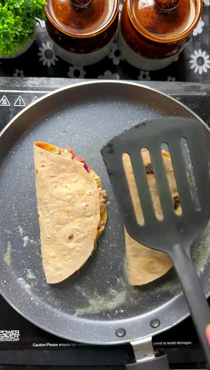 Spread butter in a pan, place the folded rotis (tacos) in the pan, and add butter on top. Flip to cook evenly.