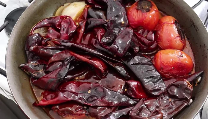 Blend the chilies, tomatoes, onion, broth from the pan, chopped garlic, 1 tablespoon of ginger, 1 teaspoon of oregano, 10 black peppercorns, and additional water until smooth.