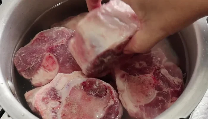 Cover the pork with water in a pot. Add 2 tablespoons of salt, 1 piece of onion, 4 bay leaves, ground oregano, and 1/4 teaspoon of marjoram. Simmer, then cook in a pressure cooker for 20 minutes (or 1 hour in a normal pot).