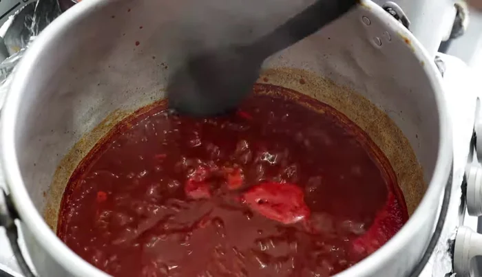In a large pot, heat a splash of oil and add the strained chili mixture. Add 2 tablespoons of granulated bouillon and 2-3 cups of water, plus 1-2 cups of the broth from the cooked pork. Simmer for 5-10 minutes.