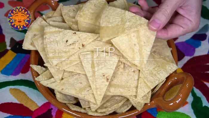 Prepare the tortilla chips: Cut day-old corn tortillas into triangles and fry until crispy.