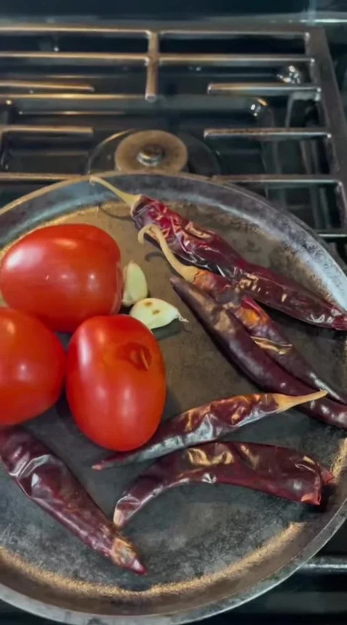 Roast tomatoes, garlic, puya chiles, and guajillo chile on a griddle until slightly charred. Remove the eyes from the dried shrimp.