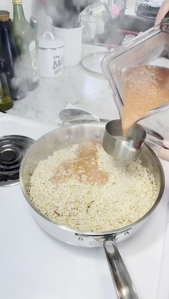 Add the remaining 5 cups of chicken broth and the tomato mixture to the rice. Stir well.