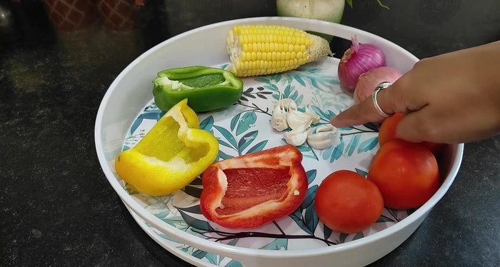Chop vegetables (tomatoes, garlic, onions, bell peppers, capsicum, corn).