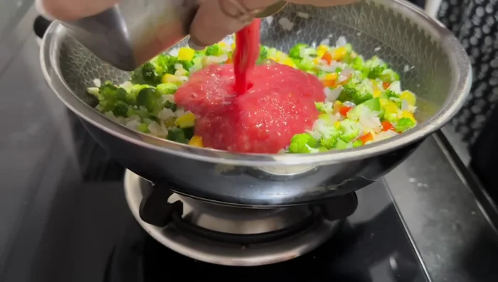 Add tomato puree, salt, and cook until the raw smell disappears.