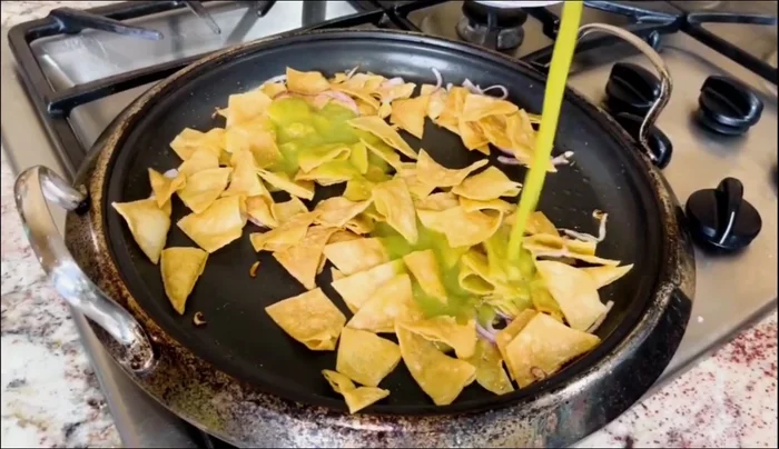 Assemble the chilaquiles: Layer tortilla chips in a bowl or plate, top with green salsa, cheese, and then the cooked egg.