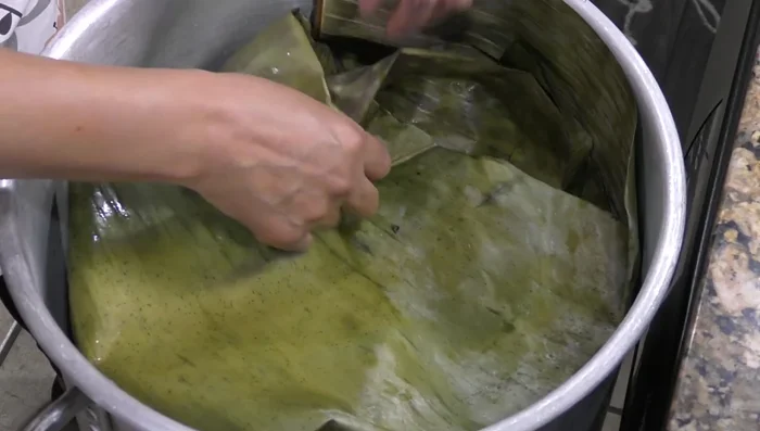Cover tightly with more banana leaves and a molcajete (or a heavy weight) to seal in steam. Cook over high heat until it boils, then reduce to low heat. (450.879) Cook for approximately 3 hours and 15 minutes. (517.64)