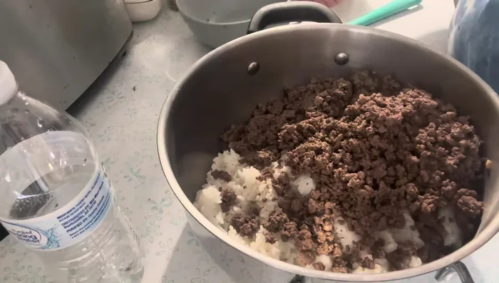 In a large bowl, combine the cooked ground beef, cooked rice, crumbled bacon, sautéed onion, tomato sauce, stewed tomatoes, garlic, salt, and pepper.