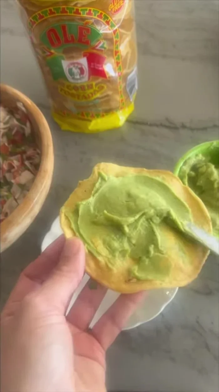 Spread smashed avocado on a tostada.