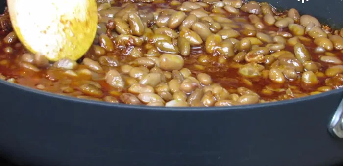 Add the cooked beans to the skillet, stir, and cover until it comes to a boil.
