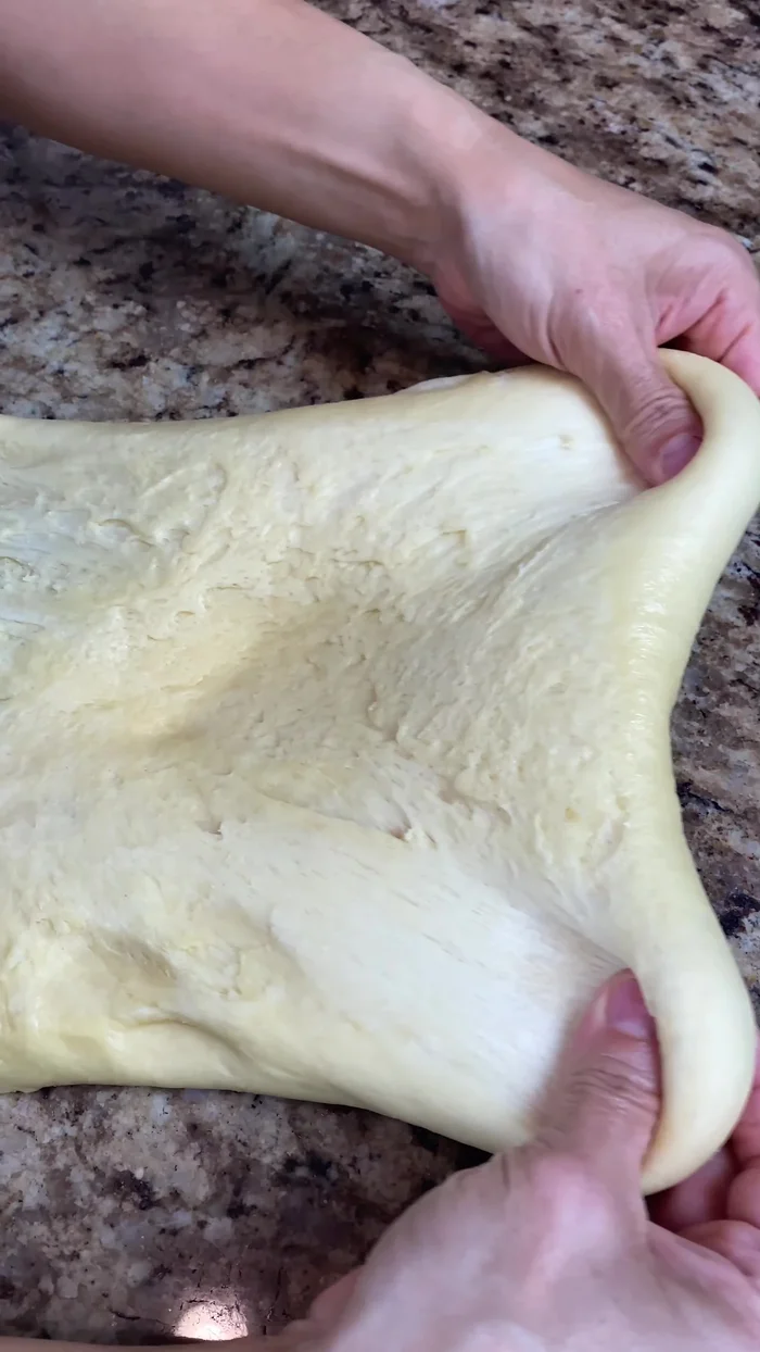 Once doubled, transfer the dough to a floured surface, roll into a square, and cut into equal parts (about 80 grams each, yielding 12 pieces). Shape them into balls and place them on a baking sheet lined with parchment paper.