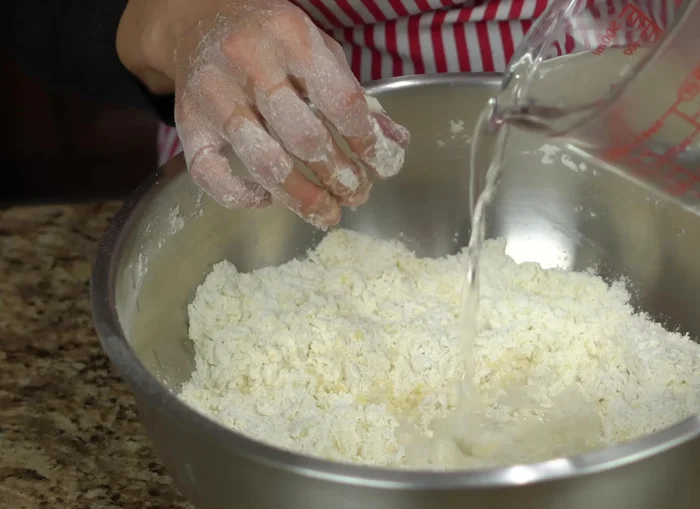Gradually add hot water to the dough, mixing until it forms a slightly sticky ball. Don't use all the water if not needed; it depends on the flour.