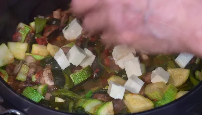 Add the cheese cubes, cover, and cook for 5 minutes until the vegetables are cooked and the cheese is softened.